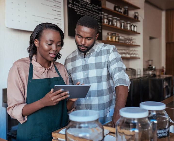 black women holding tablet talking with black made in a shop