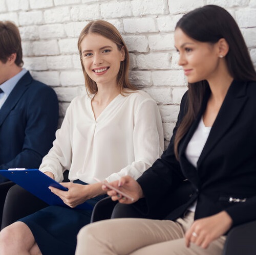 Young smiling girl in blue suit is sitting in waiting room.