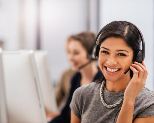 woman with headset on infront of computer smiling
